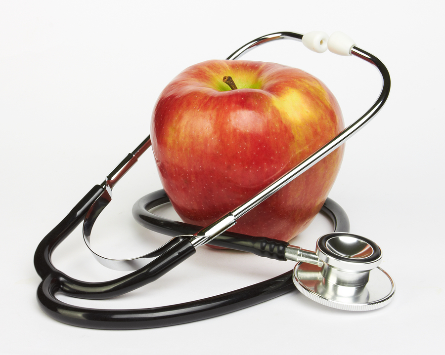 Apple and stethoscope on white background