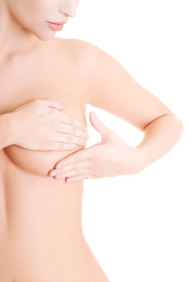 Caucasian adult woman examining her breast for lumps or signs of